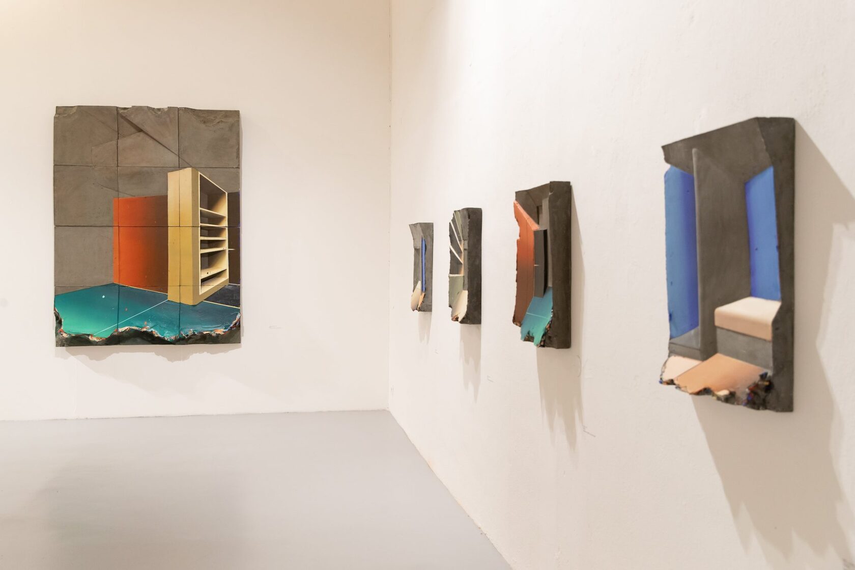 Four painted panel works spaced along a white gallery wall, each at a measured distance from the next.
